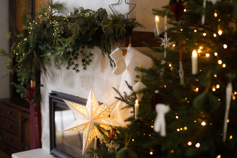 Christmas mantel decorated with christmas star, stockings, greenery.
