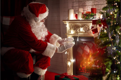 Santa by fireplace and Christmas tree.