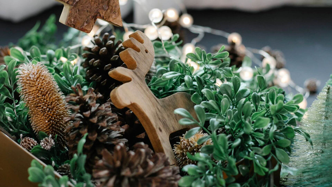Festive wooden reindeer decoration among pine cones and greenery.