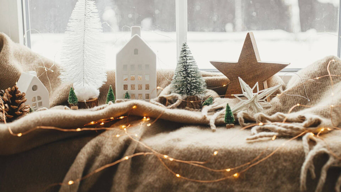 Cozy window sill with winter decor, lit stars, and snowy view outside.