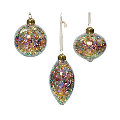 Three Christmas ornaments made of clear glass and filled with multicolored sequins, hanging from gold-colored caps with ribbons. The ornaments are spherical, teardrop-shaped, and elongated.