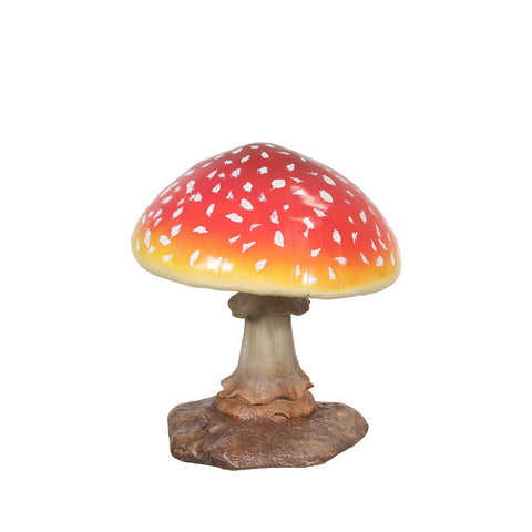 A realistic model of a red and yellow toadstool mushroom with white spots on its cap, displayed on a brown base.