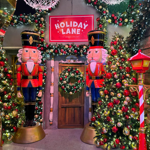 A festive display titled "Holiday Lane" features two large nutcracker statues, a wreath-adorned door, and decorated Christmas trees with lights and ornaments.