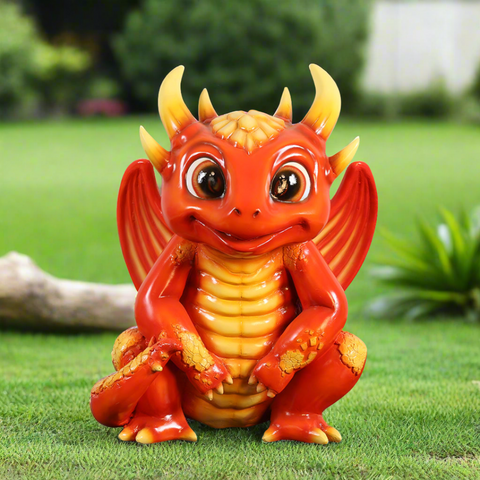 Adorable red dragon statue sitting on grass, smiling.