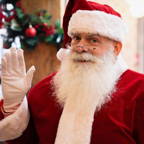 Santa Claus waving, with glasses and a fluffy white beard.